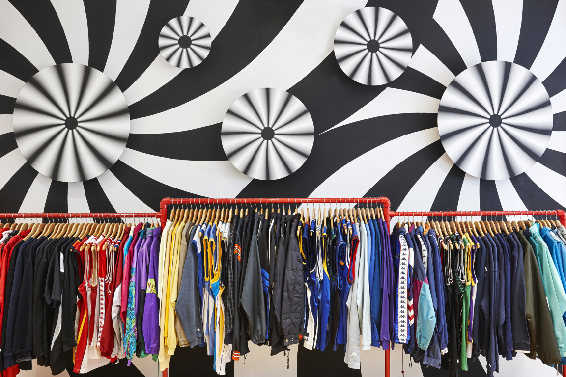 Colorful vintage clothing hangs on racks in COW's new flagship store in Leeds, showcasing a modern and stylish retail environment.