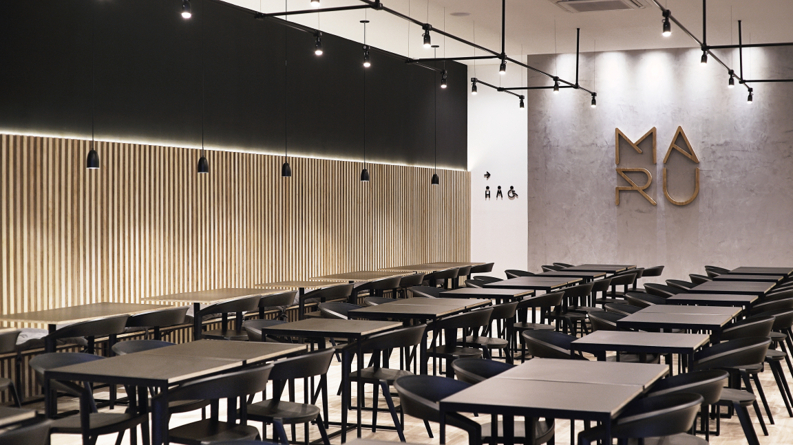 Modern interior of Maru Asian Cuisine in Curitiba, featuring dark wooden tables and decorative wall panels.