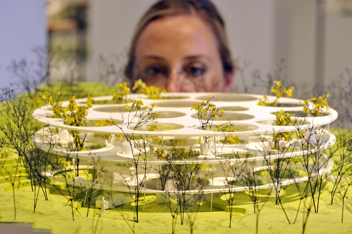 A member of staff at Japan House London inspects Beton Hala Waterfront Centre, one of 100 exhibits on display in the inaugural exhibition, Futures of the Future by acclaimed Japanese architect Sou Fujimoto