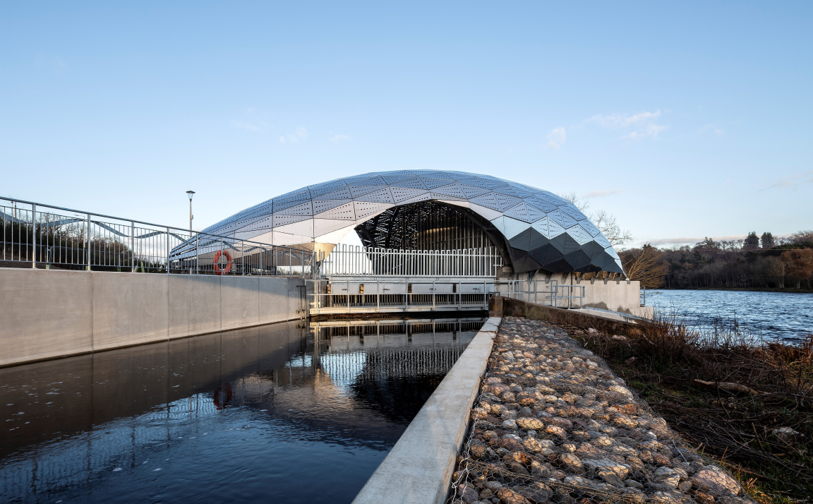 Modern architectural structure beside a river, showcasing innovative design and connection to community and environment.