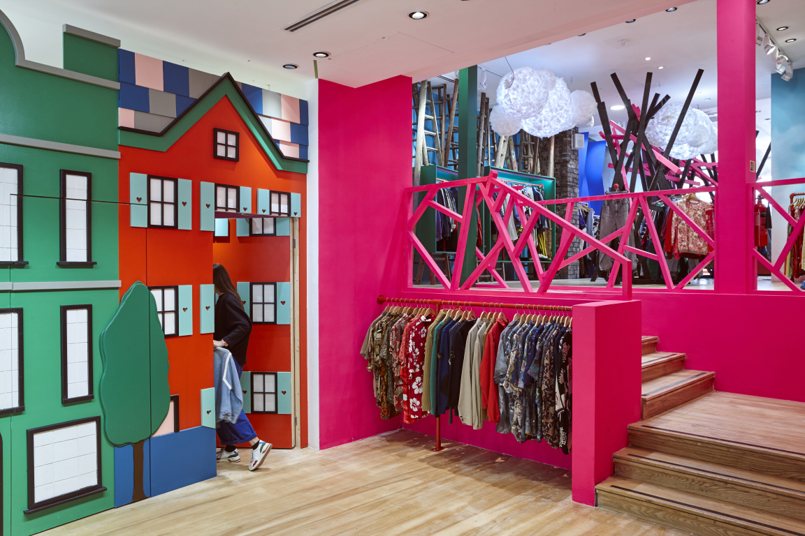 Colorful interior of COW's flagship vintage store in Leeds, featuring vibrant walls and a diverse clothing display.