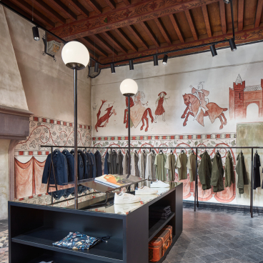 Contemporary COEF clothing shop interior featuring historical murals, stylish apparel displays, and modern lighting in Utrecht.