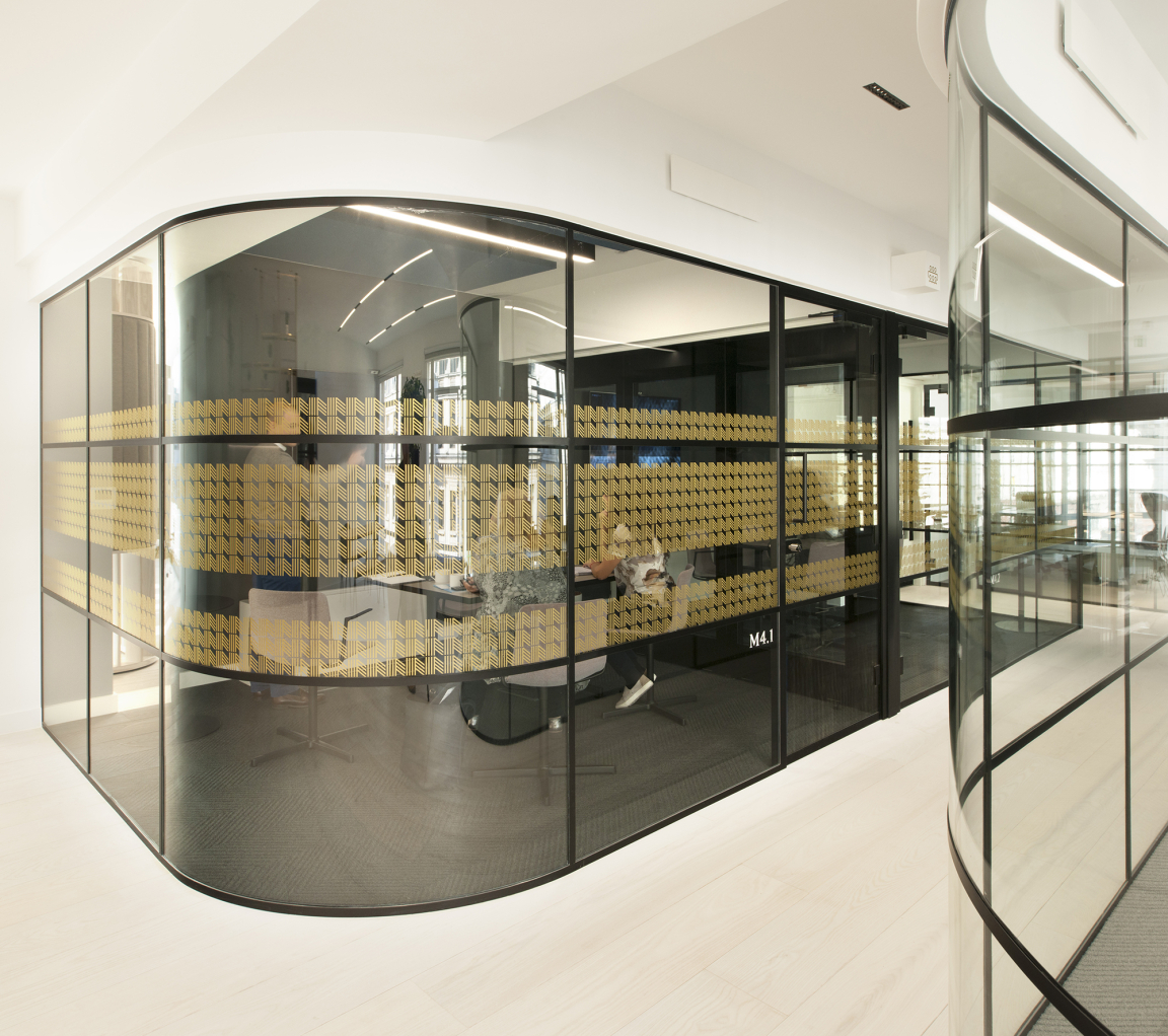 Modern office design featuring curved glass walls and unique yellow-patterned elements, showcasing the Material Source Studio collaboration.