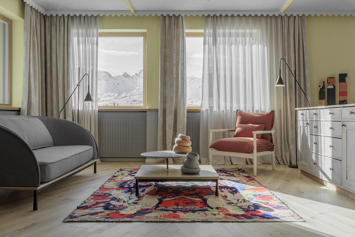 Living area ©Gustav Willeit  Drapery fabrics by Clarke&Clarke. Arc Sofa by Stellar Works. Arc coffee table by Stellar Works. Colate Vases by Niva Design. “Flying Carpets B02_20/10_2021” in digital collage textile Jacquard Gobelin by Elisa Grezzani. Sergia armchair by Miniforms. Original Icaro lodge sideboard. “Polychromos” figurative wood carvings by Hubert Kostner. 