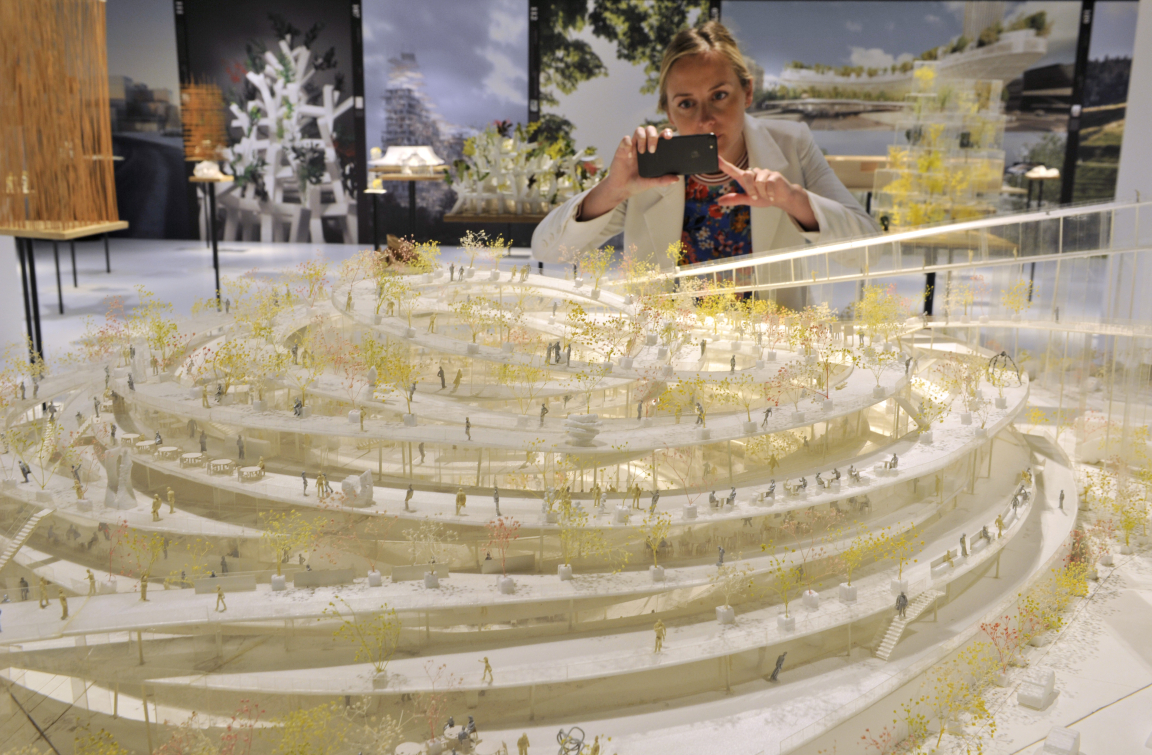 A member of staff at Japan House London inspects Beton Hala Waterfront Centre, one of 100 exhibits on display in the inaugural exhibition, Futures of the Future by acclaimed Japanese architect Sou Fujimoto