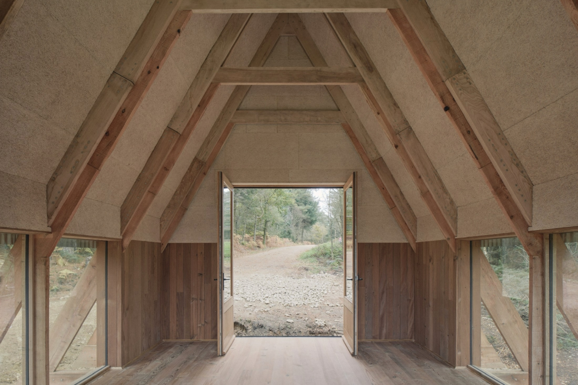 Innovative interior of Clearfell House showcasing British timber structure and natural surroundings through open door.