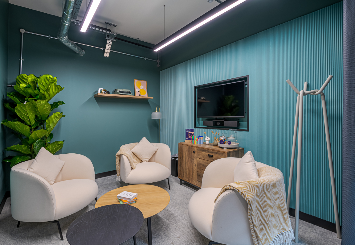 Contemporary co-working space featuring inviting seating, decorative accents, and vibrant teal walls, designed by Two.