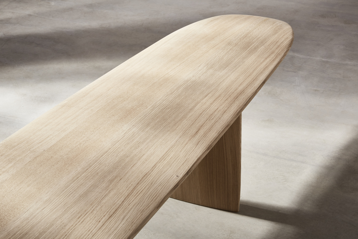 Stylish wooden table design by Benchmark, showcasing natural grain and elegant curves, recognized in the UK's Wood Awards.