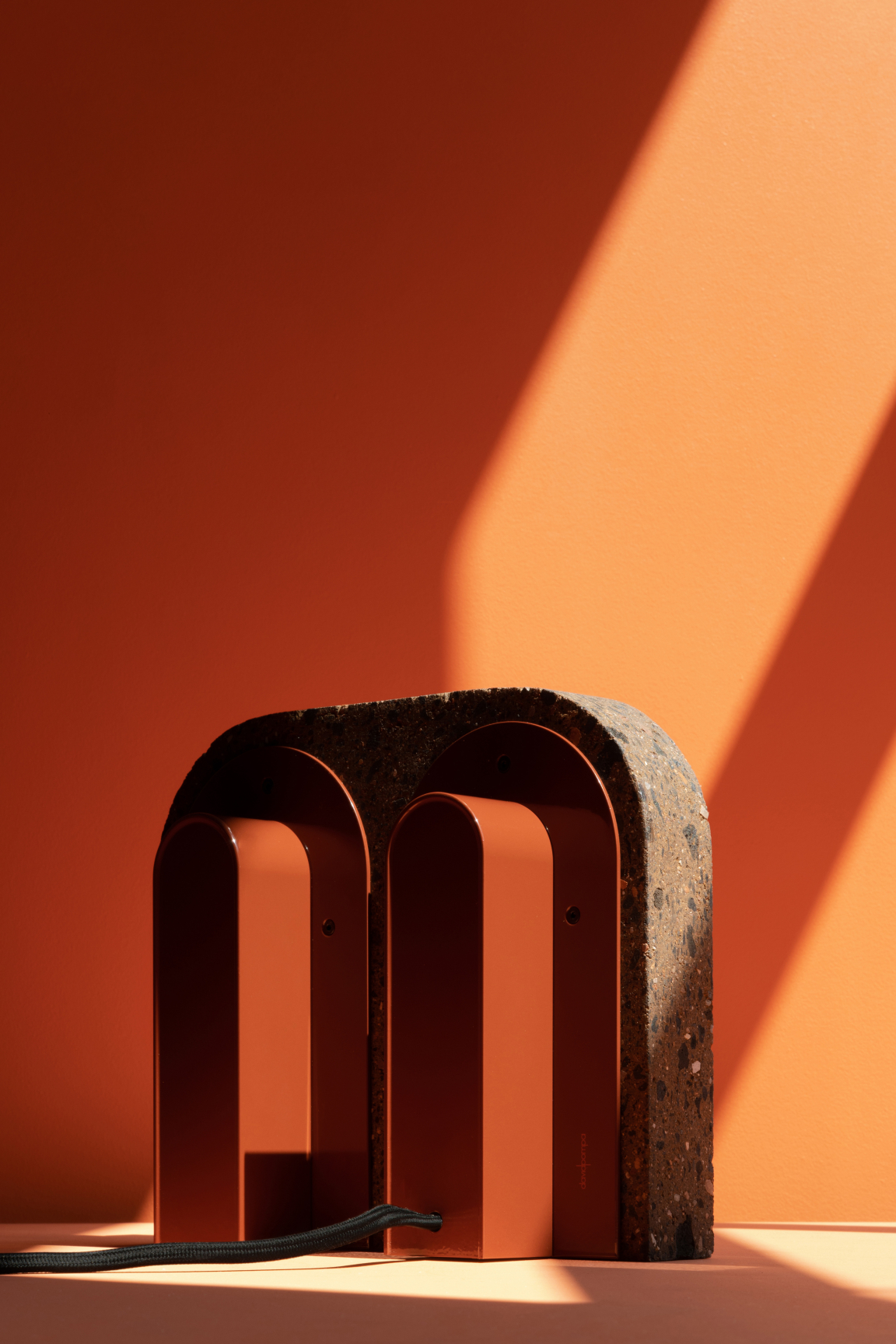 Volcanic stone and minimalist candle holders by davidpompa showcase innovative design in a vibrant orange setting.