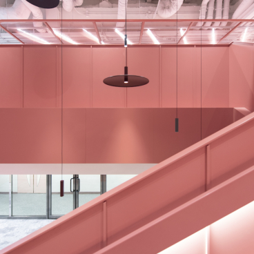 Modern pink workspace design featuring elegant lighting and an open stairway at Jardine Restaurant Group by Bean Buro.