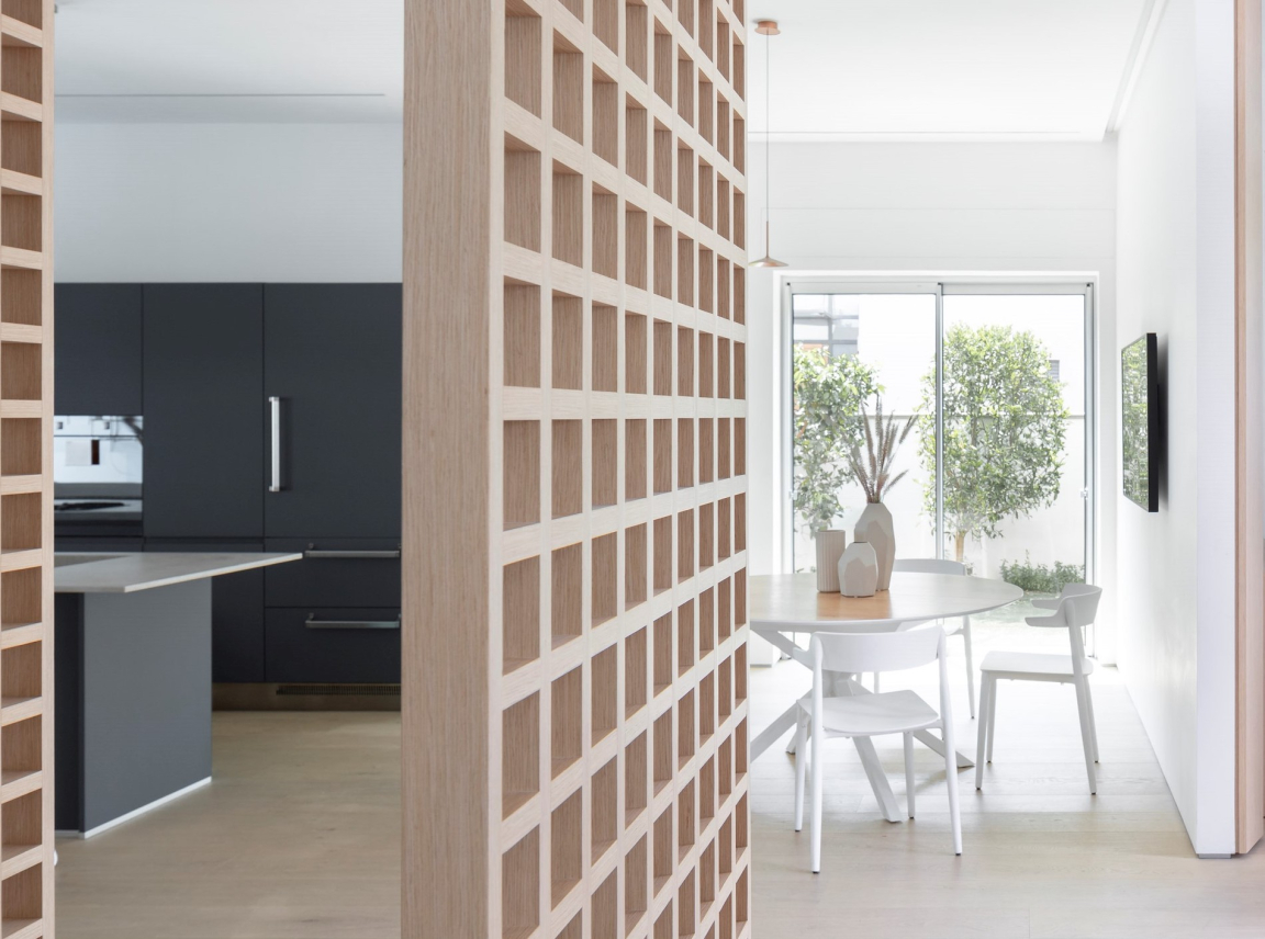 Modern home office featuring stylish wooden partition, sleek kitchen, and a bright dining area with natural light.