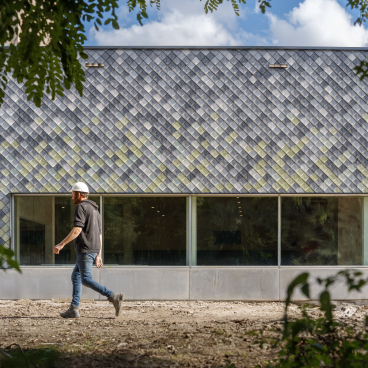 A construction worker walks by a building featuring innovative sustainable materials for circular construction.