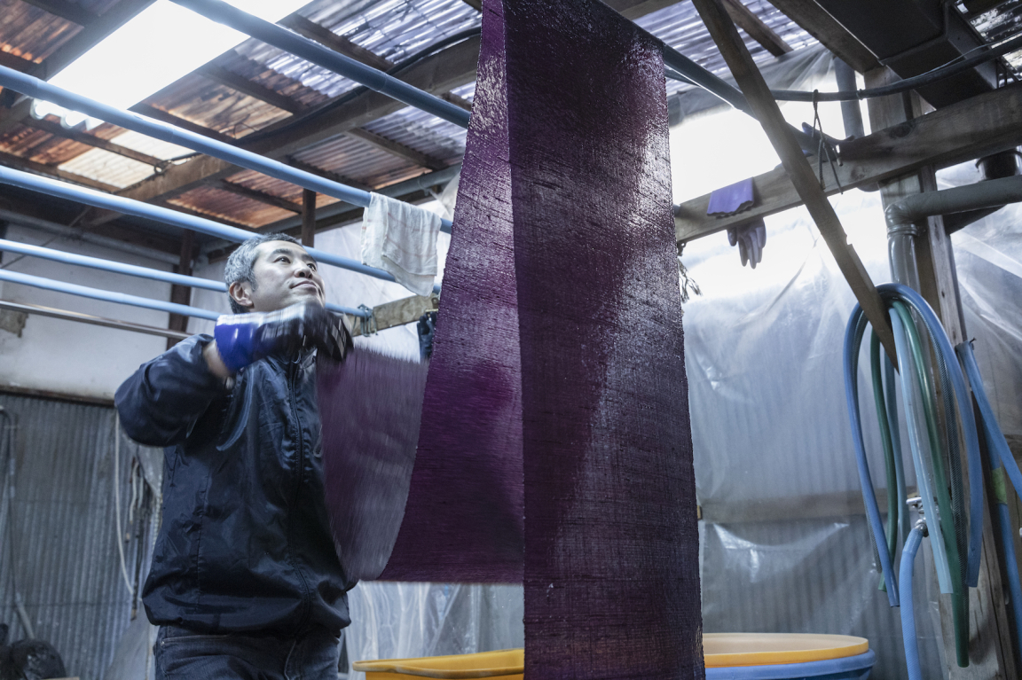 OGAWA Koji dyer at Yoshioka Dyeing Workshop hangs dyed textiles - see Living Colours exhibition 5 April-19 May at Japan House