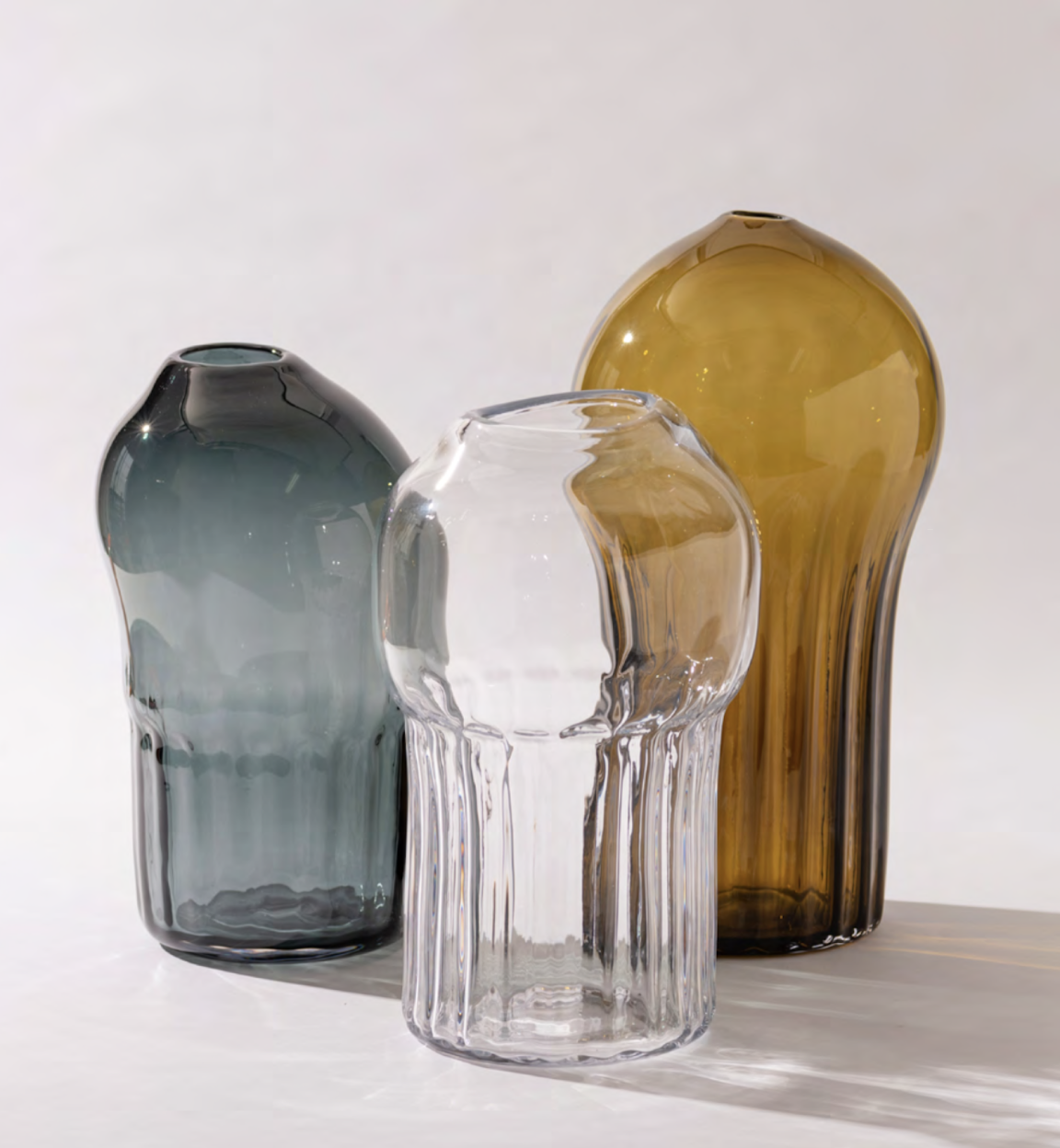 Three artistic glass vases in varying colors showcase the craftsmanship of Mexican artisans, highlighting vibrant design.