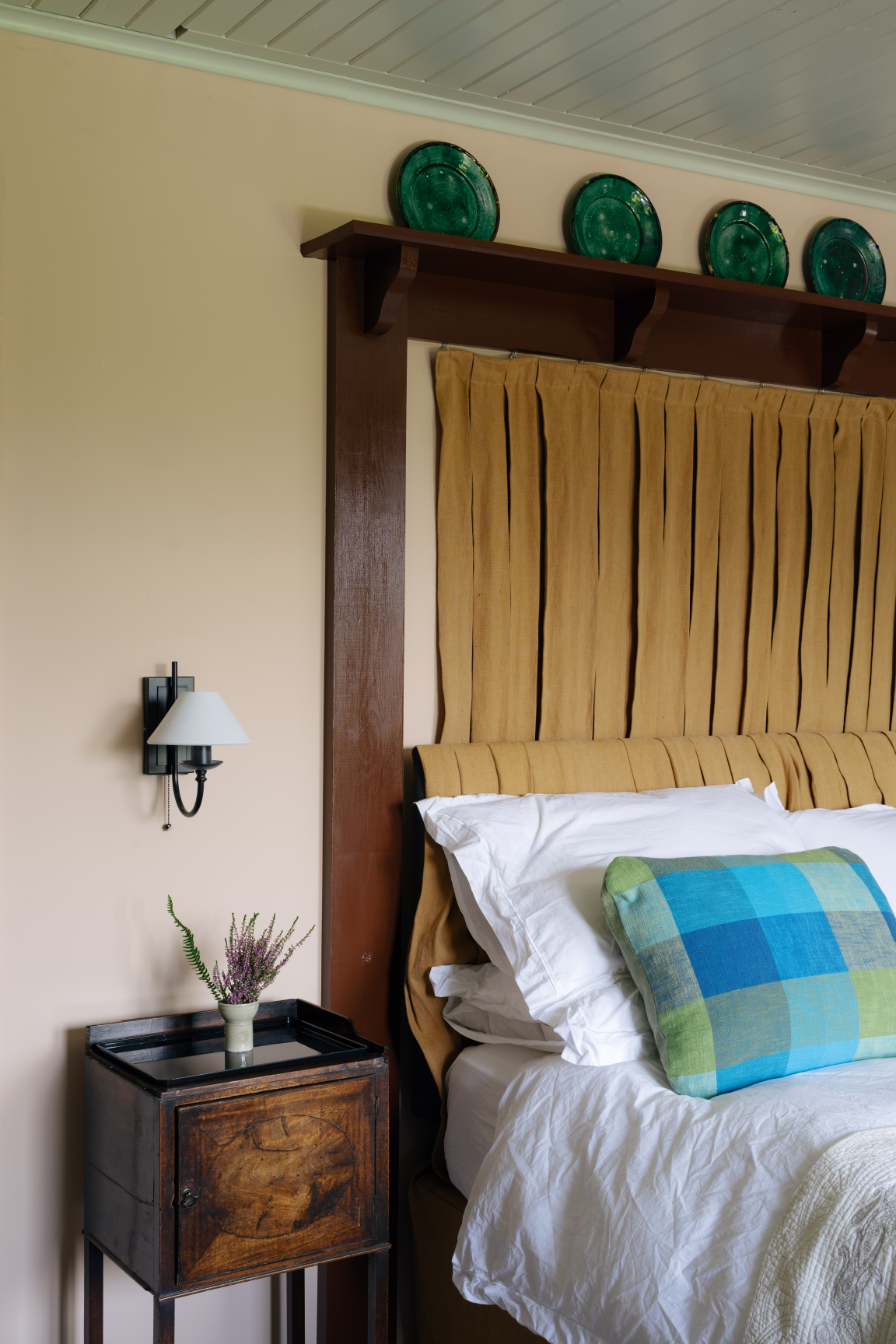 Cozy bedroom featuring a brown tufted headboard, colorful accent pillows, and Scandinavian-inspired decor elements.