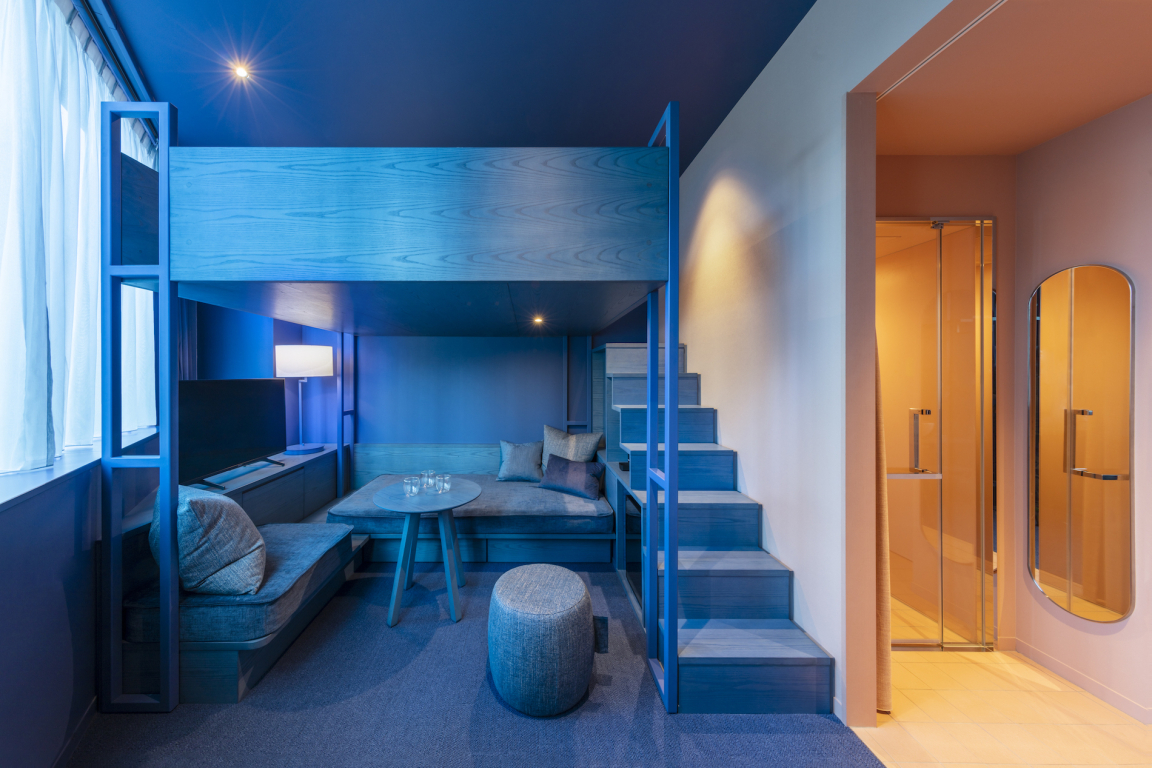 Stylish hotel room at Toggle Hotel Tokyo featuring a lofted sleeping area and modern furnishings in a vibrant blue palette.