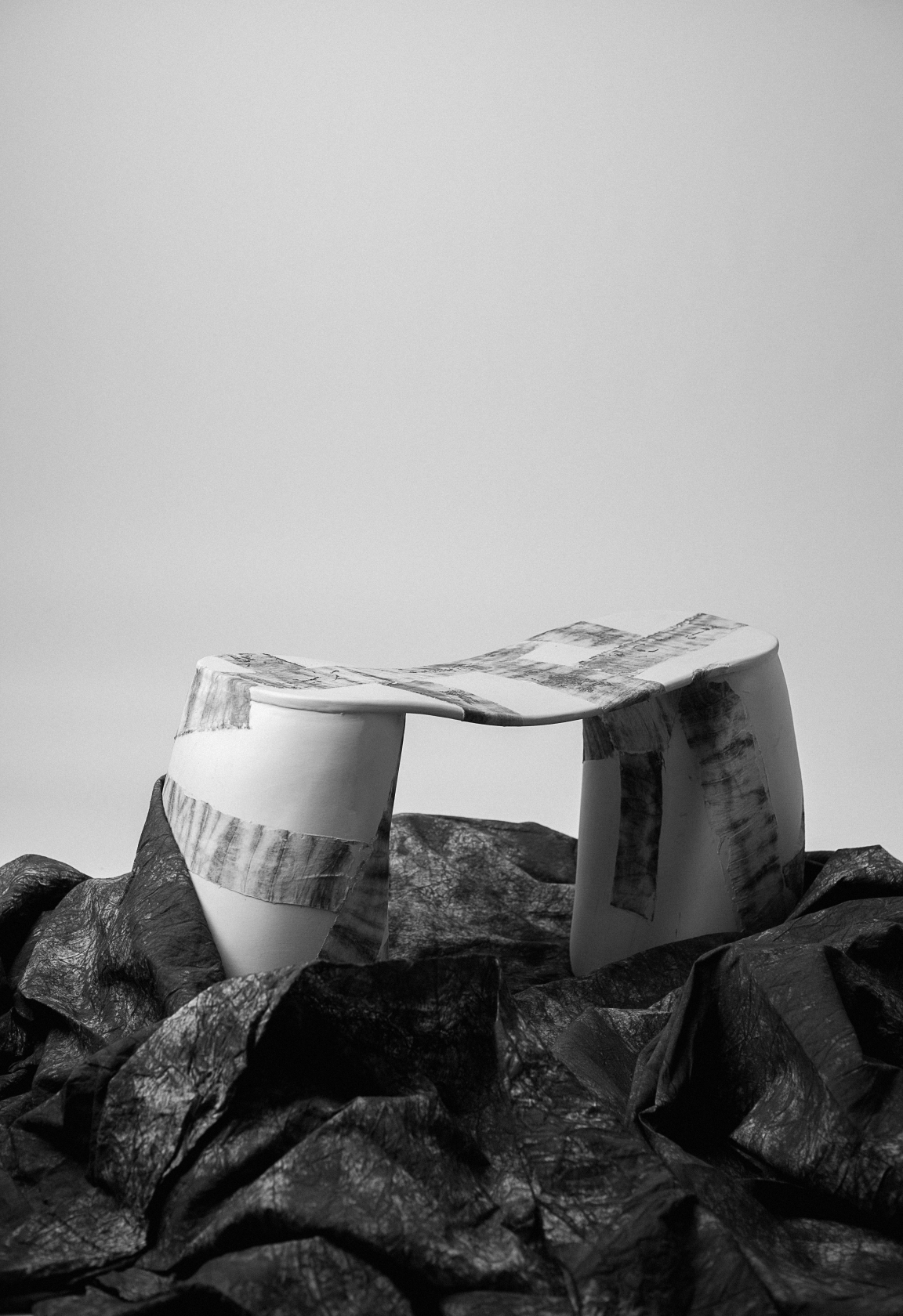 Sculptural furniture piece made from coffee waste, showcasing human-centric design against a textured black background.