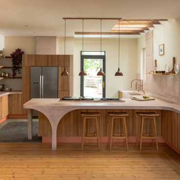 Modern kitchen design featuring poured pink concrete and Scottish Oak cabinetry, showcasing a stylish, curved countertop and warm wood accents.