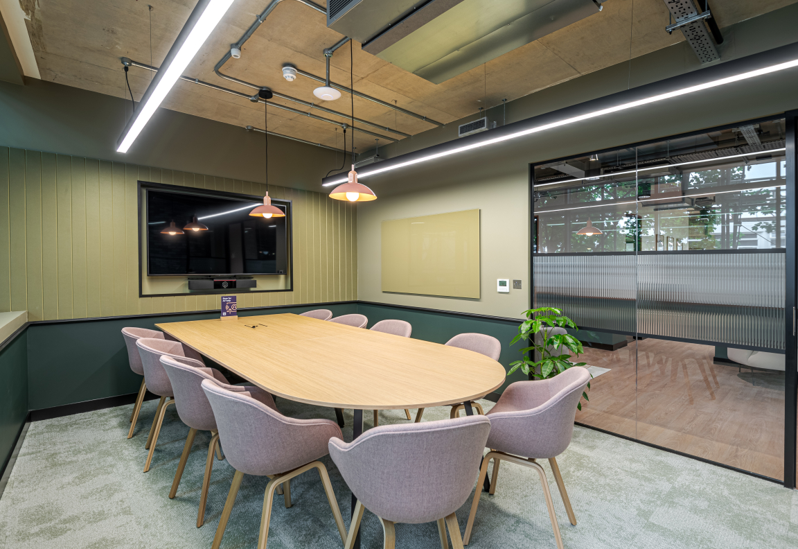 Modern co-working space featuring a large table surrounded by chairs, designed for collaborative meetings.