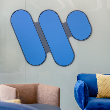 Colorful Warner Music logo displayed on a modern office wall, surrounded by stylish seating in an innovative workplace design.