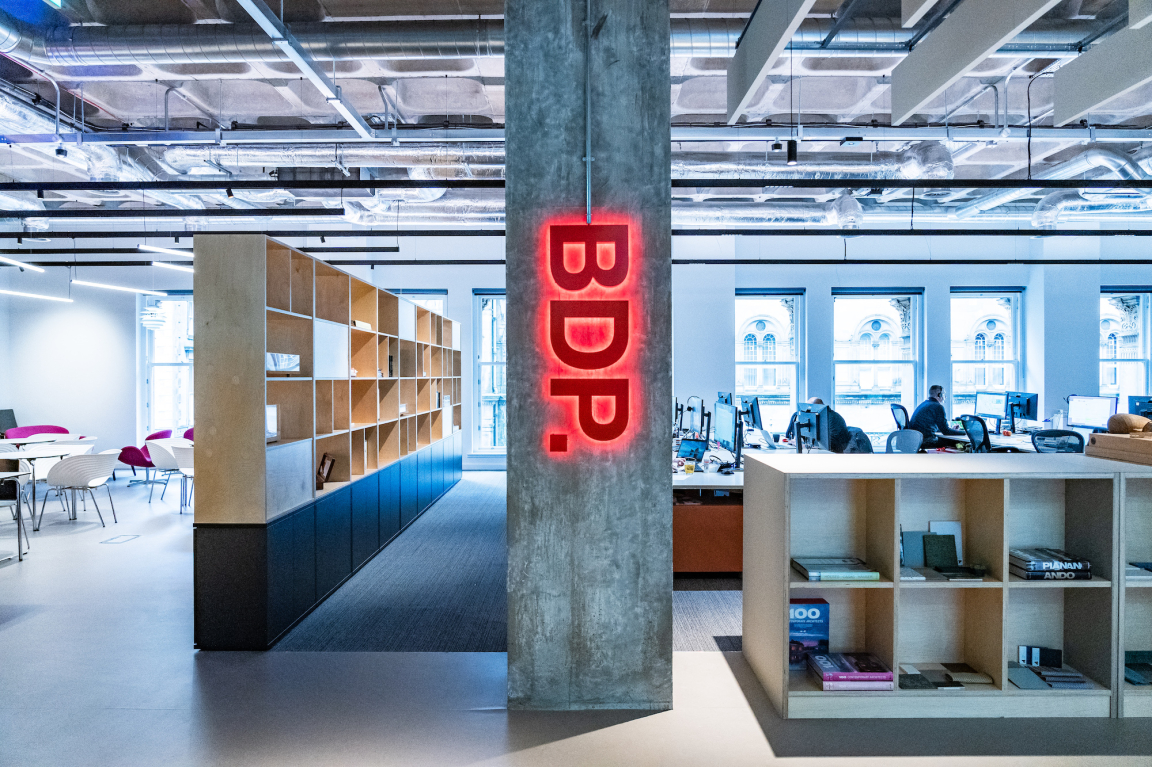 Brightly lit BDP Glasgow studio interior features modern design elements, open workspaces, and a striking illuminated BDP sign.