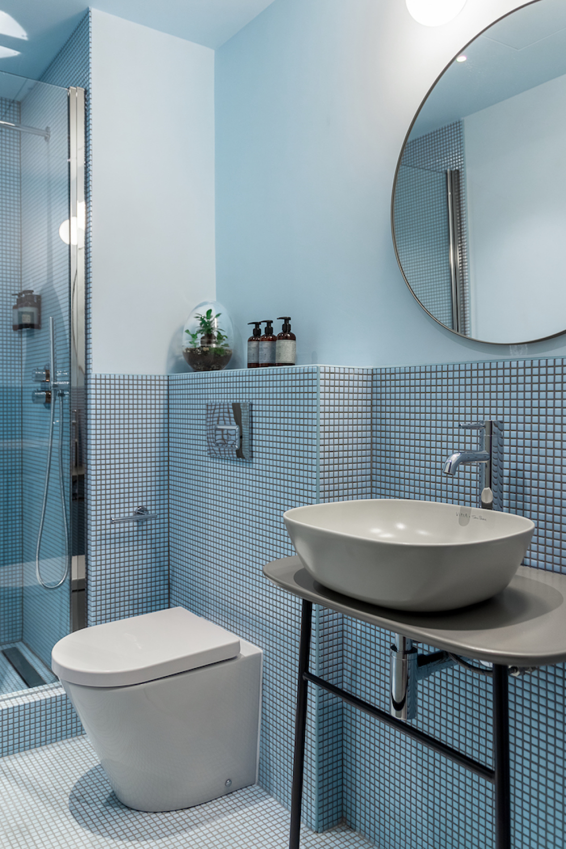 Bright blue bathroom featuring a modern vessel sink, stylish shower, and eco-friendly design elements, reflecting Locke's sustainable aesthetic.