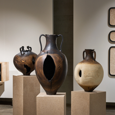 Artistic wooden vases crafted from Scottish ash, displayed prominently in a gallery setting, highlighting material intelligence.