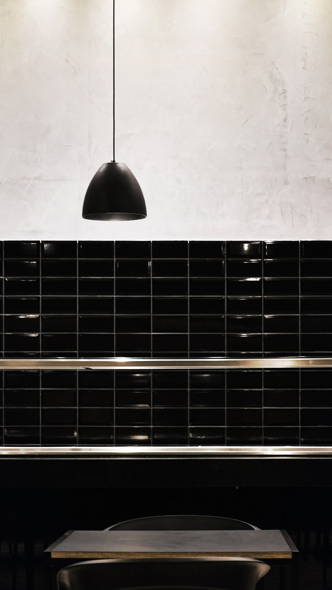 Intimate dining interior of Maru Asian Cuisine featuring black tiles and a stylish pendant light in Curitiba.