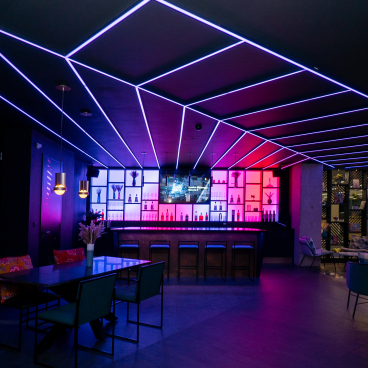 Modern bar interior featuring dynamic lighting and colorful backlit shelves at the Pixel Artworks London showroom.