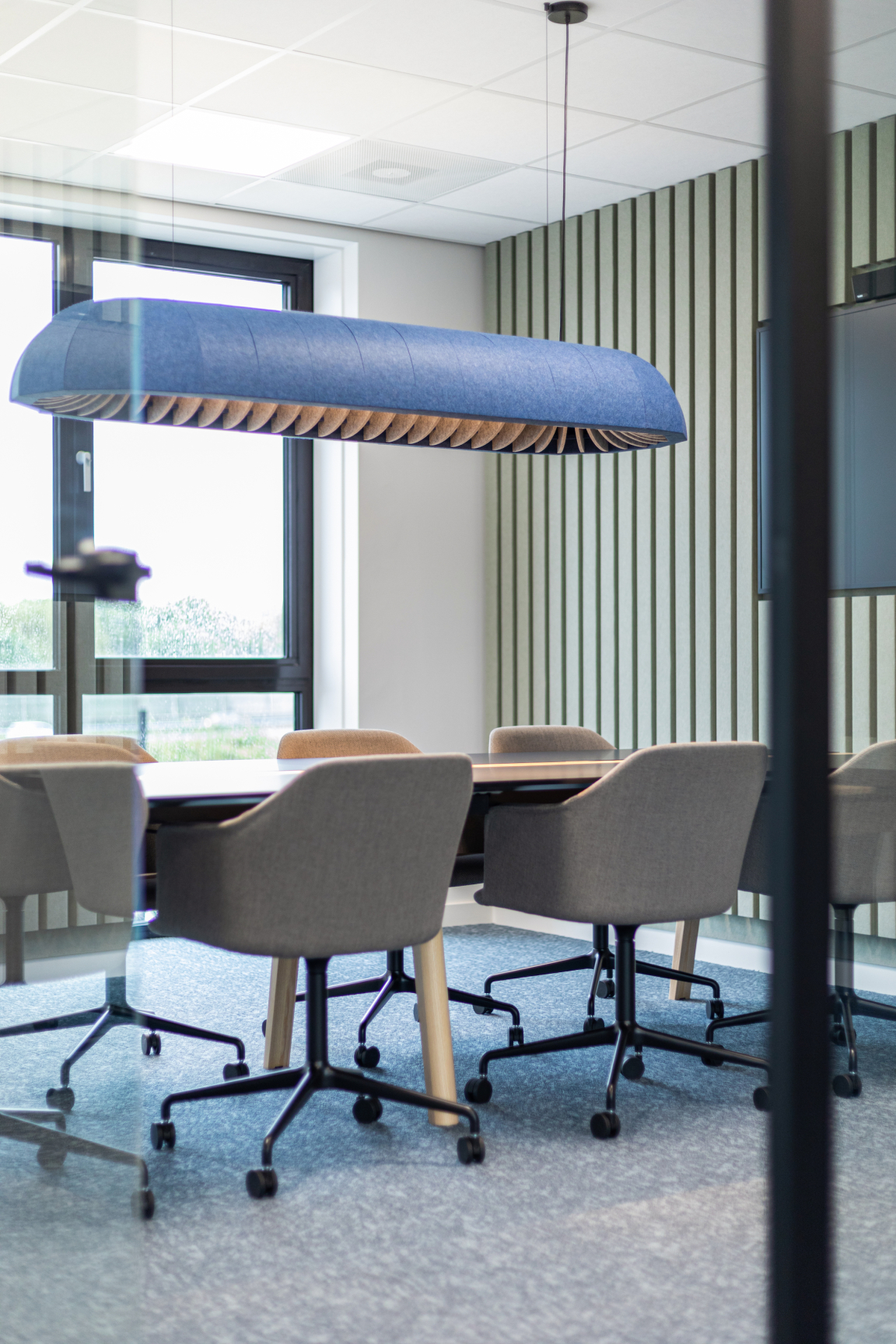 Lumenear acoustic lighting hangs above a modern conference table in a stylish, well-lit office space.