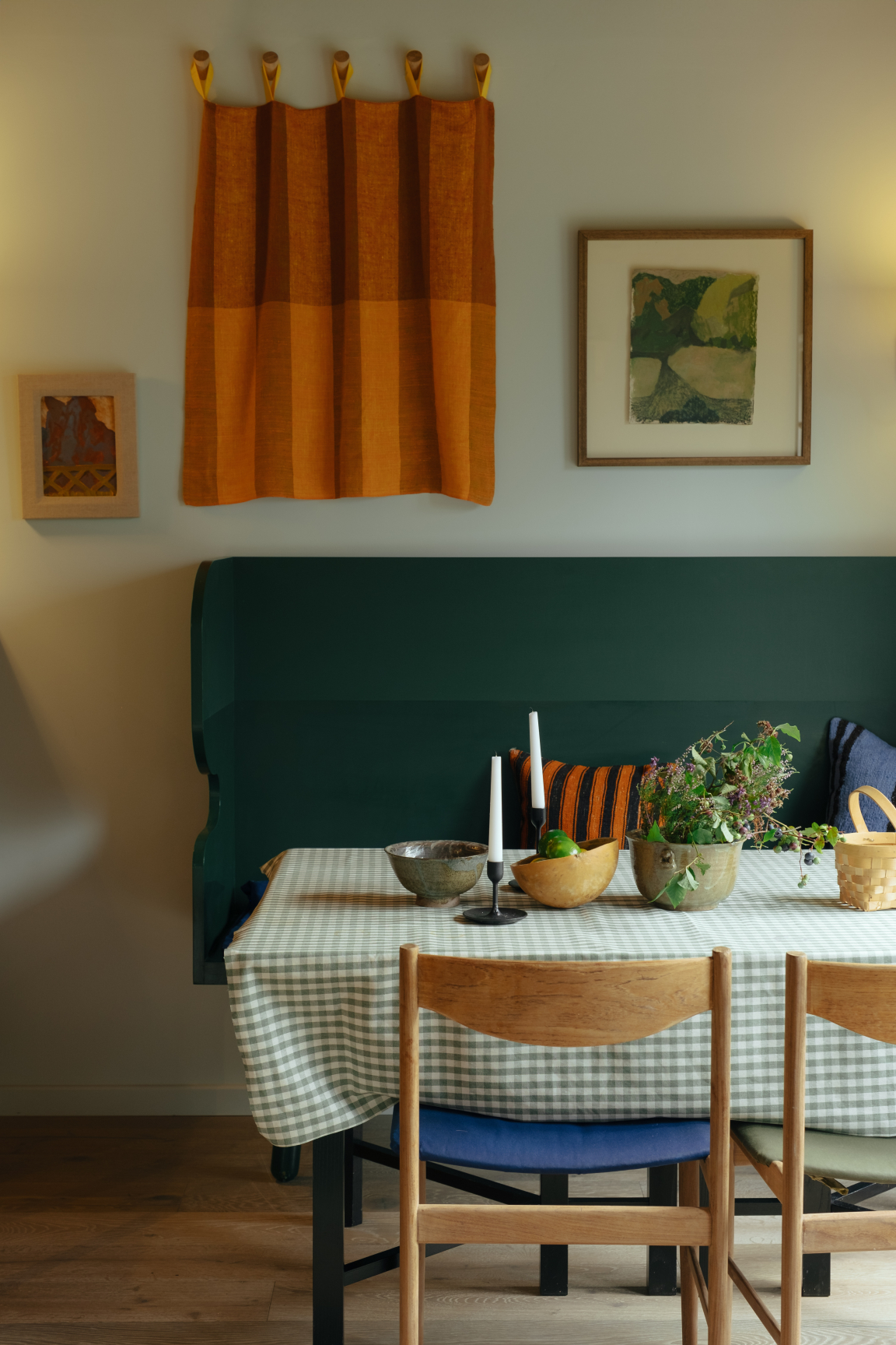 Welcoming dining area featuring Scandinavian-inspired decor, green bench, checkered tablecloth, and decorative bowls with natural elements.