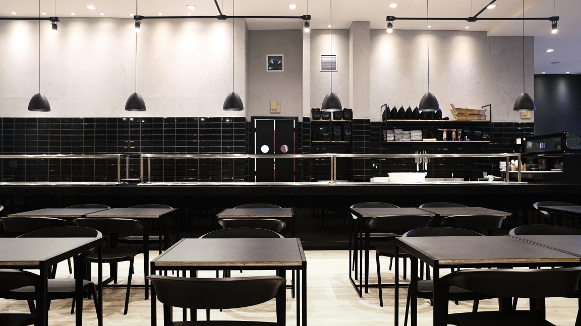 Elegant interior of Maru Asian Cuisine, featuring minimalist black furniture and atmospheric lighting in Curitiba.