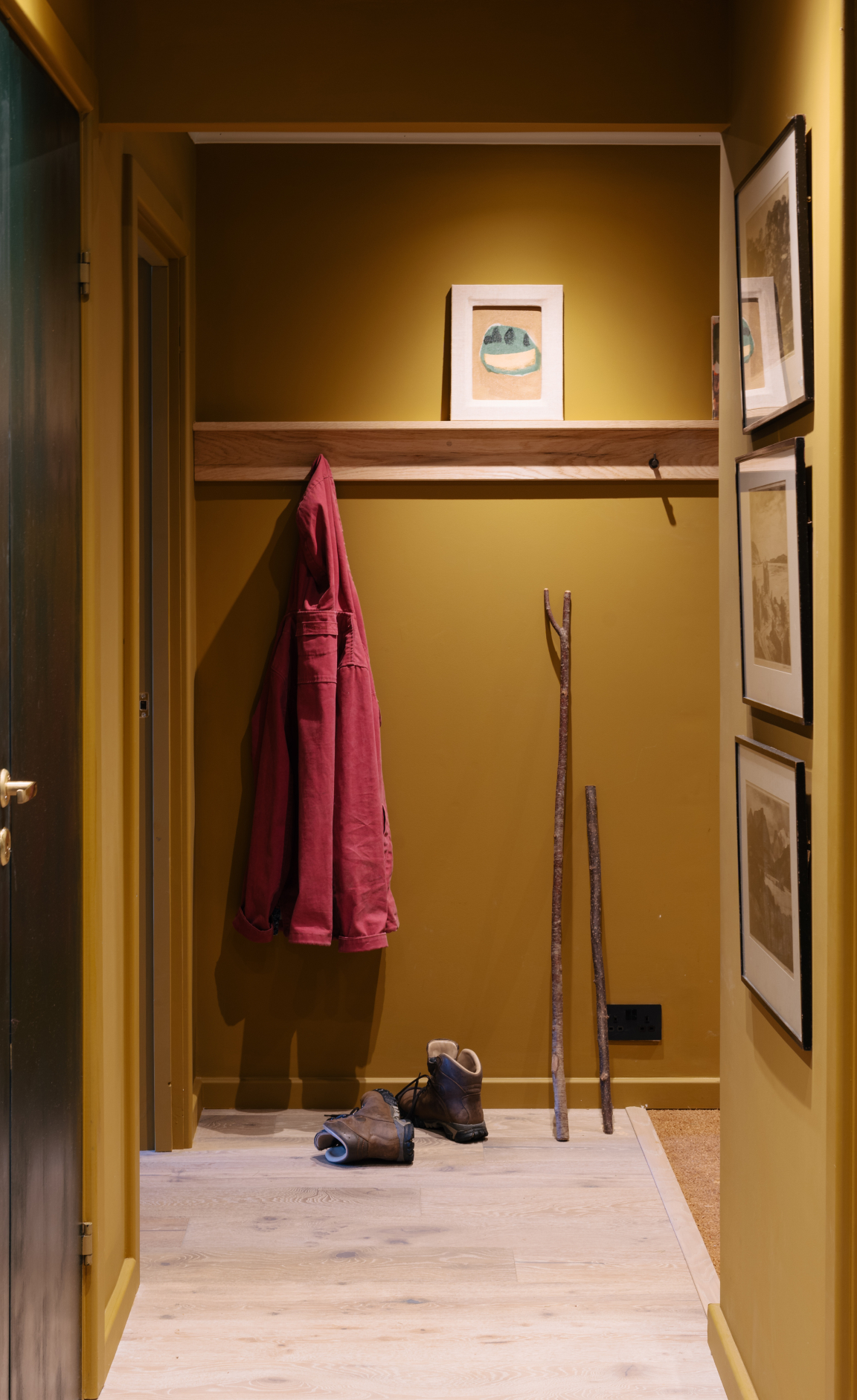 Welcoming interior hallway with a yellow backdrop, featuring a coat, boots, and artworks inspired by Scandinavian design.