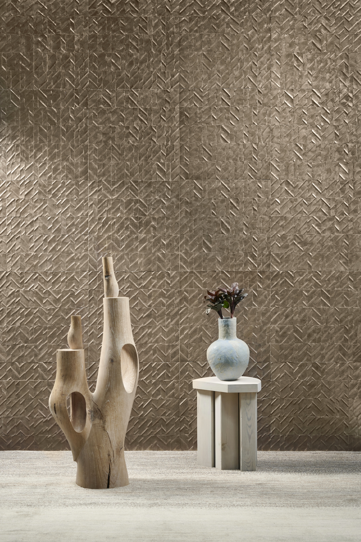 Textured wallcovering with elegant wooden sculptures and a ceramic vase, showcasing Arte's sophisticated Spring collections, Luster & Merino.