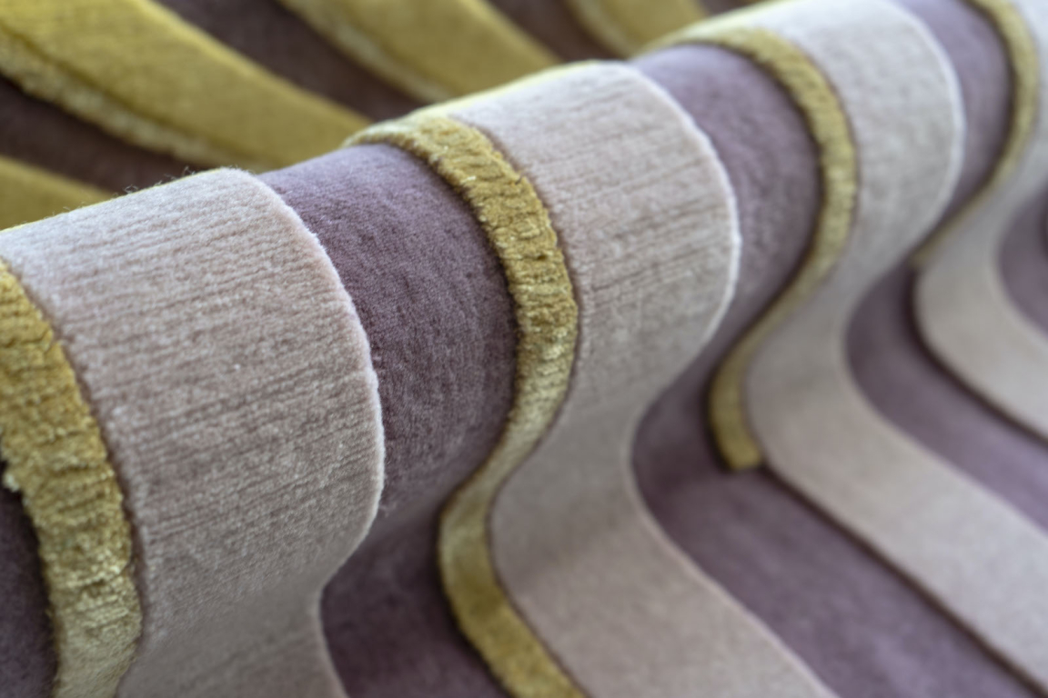 Textured fabric showcasing artisan craftsmanship in vibrant purple, beige, and olive green patterns.