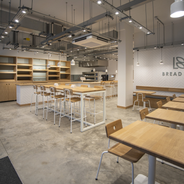 Minimalist interior of Bread Lab Bakery in London, featuring wooden furniture and modern lighting design by Liqui Group.