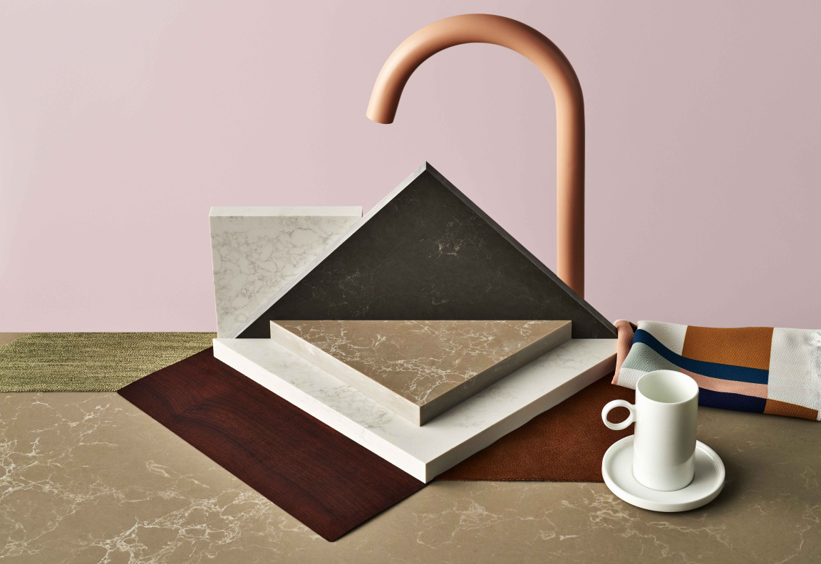 Stylish quartz surfaces in various colors and textures complement a modern kitchen setting with a unique faucet and cup.