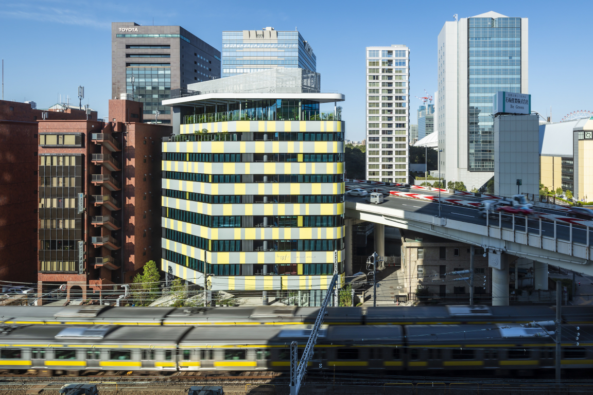 View of Toggle Hotel Tokyo's modern architecture set against an urban backdrop with railway and busy streets.