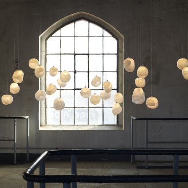 Hanging porcelain light fixtures create an ambient glow in an industrial space, reflecting contemporary German design innovation.