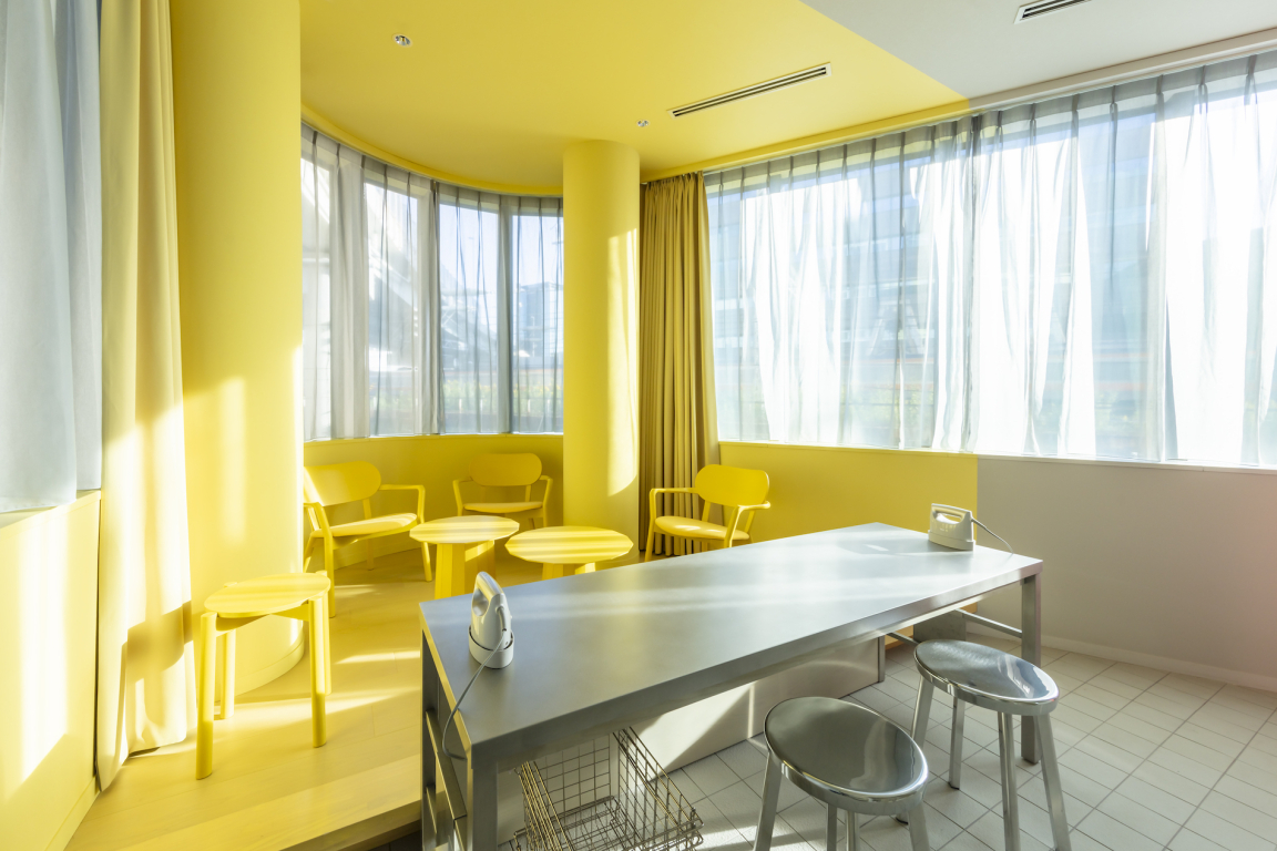 Bright yellow lounge area with modern furniture and large windows, showcasing the urban design of Toggle Hotel Tokyo.