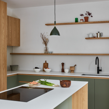 Modern kitchen with green cabinetry, natural wood accents, and stylish decor, showcasing a connection to nature in design.