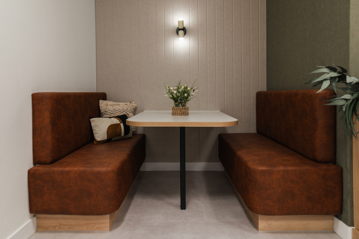 Calming breakout area featuring cozy brown seating, a minimalist table, and decorative plants at The Hive workspace.