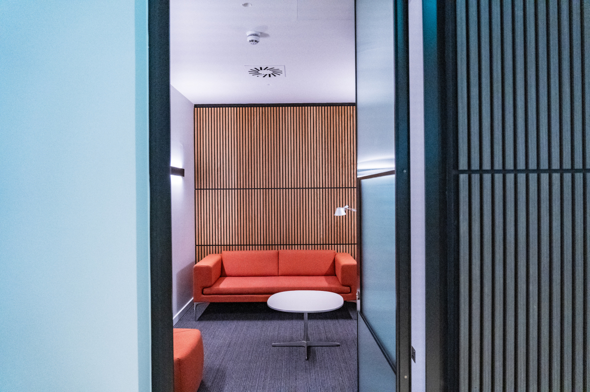 Modern meeting space in BDP Glasgow's new studio, featuring orange furniture and wooden wall accents.