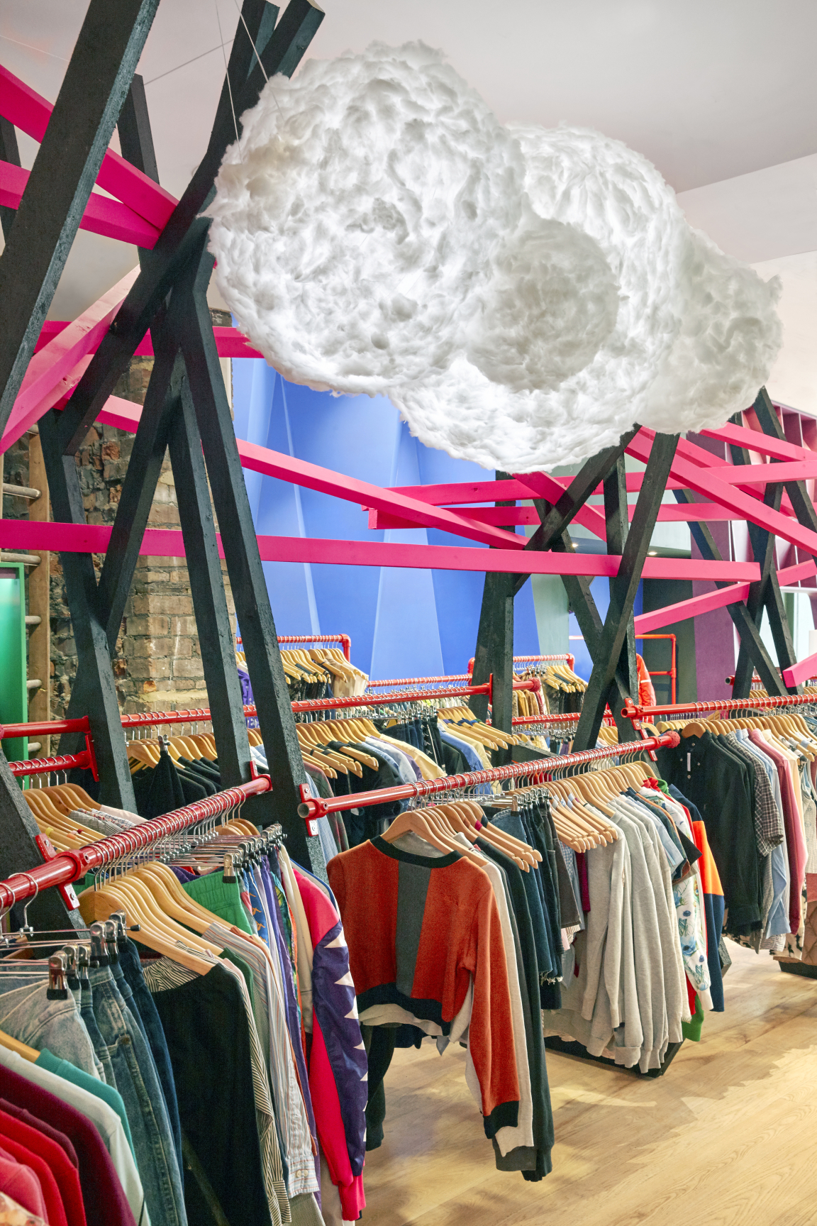 Stylish vintage clothing racks adorned with colorful apparel inside COW's new flagship store in Leeds.