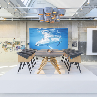 Sustainable furniture displayed in a modern showroom featuring artwork of a whale and stylish wooden dining chairs.