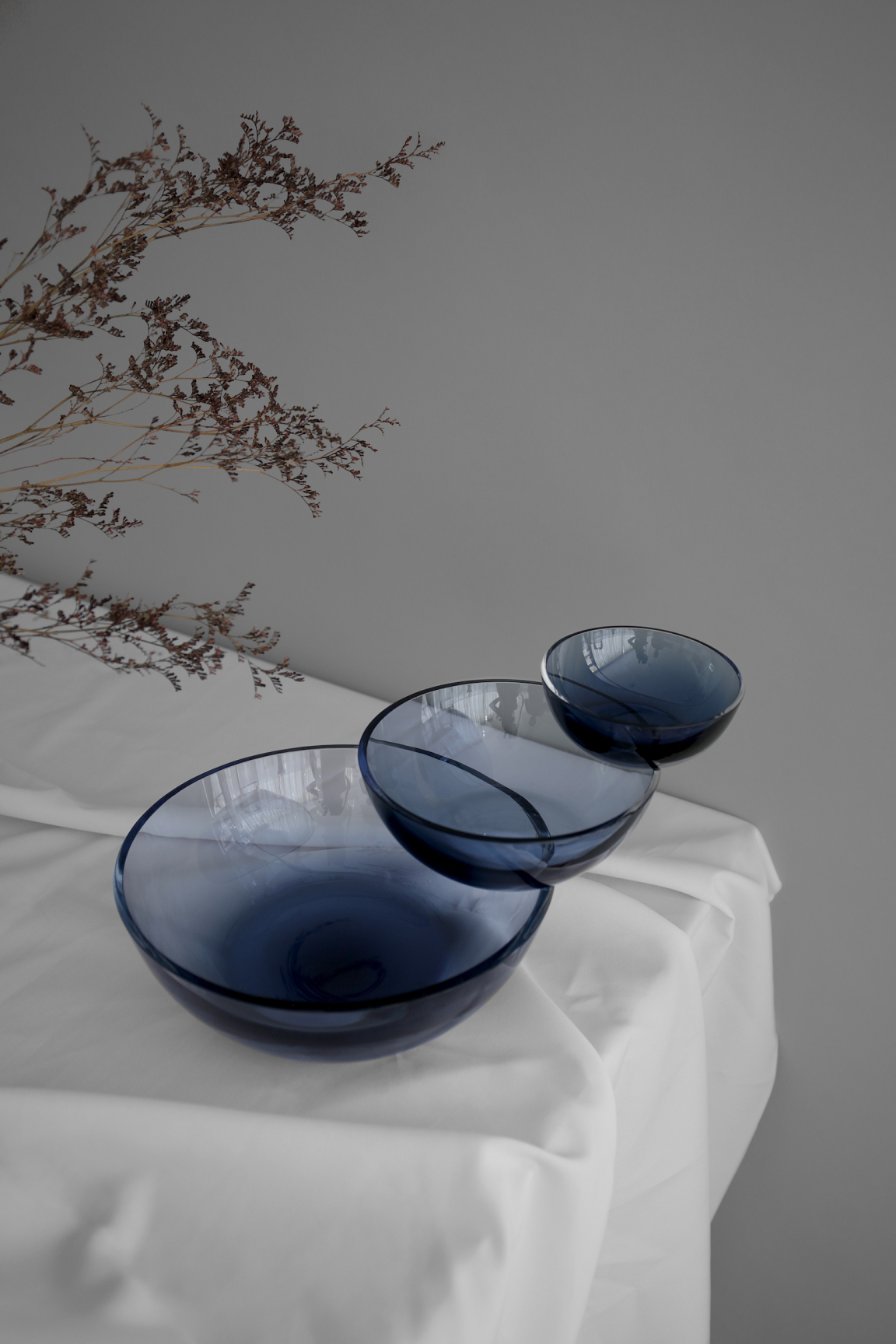 Elegant blue glass bowls arranged in a gradient on a white tablecloth, highlighting Mexican artisan craftsmanship.