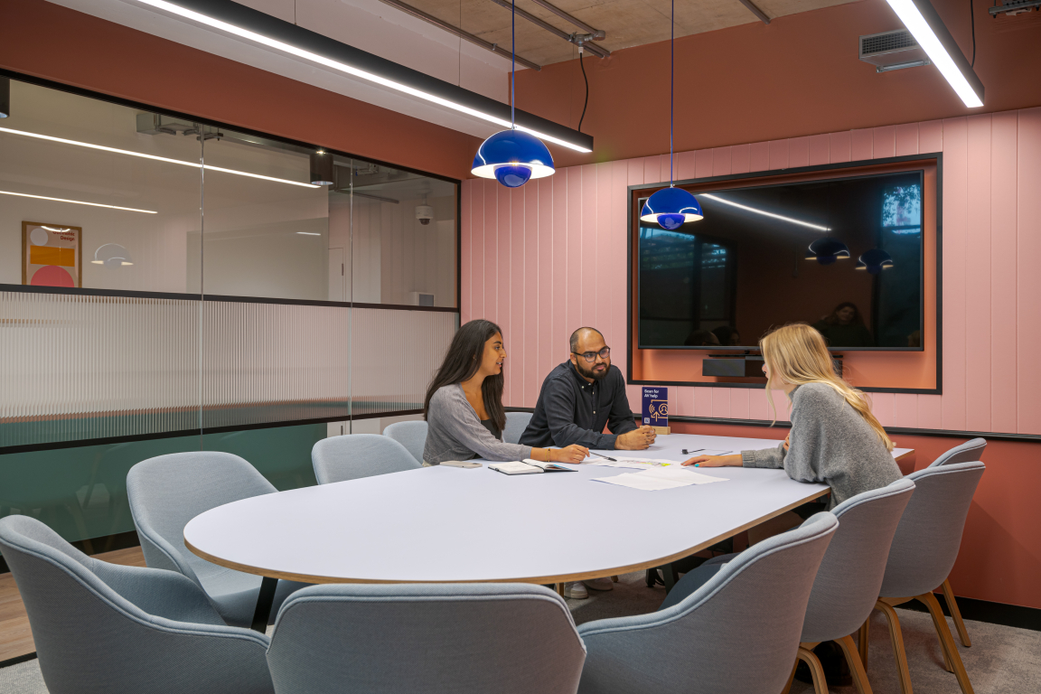 Collaborative meeting in a modern co-working space featuring a unique oval table and contemporary decor.