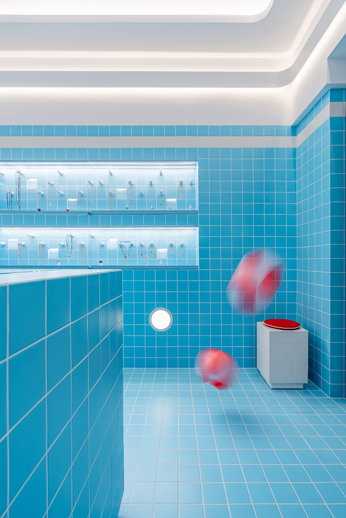 Vibrant blue tiled room featuring decorative items, accented by floating red spherical objects for a bold color inspiration.