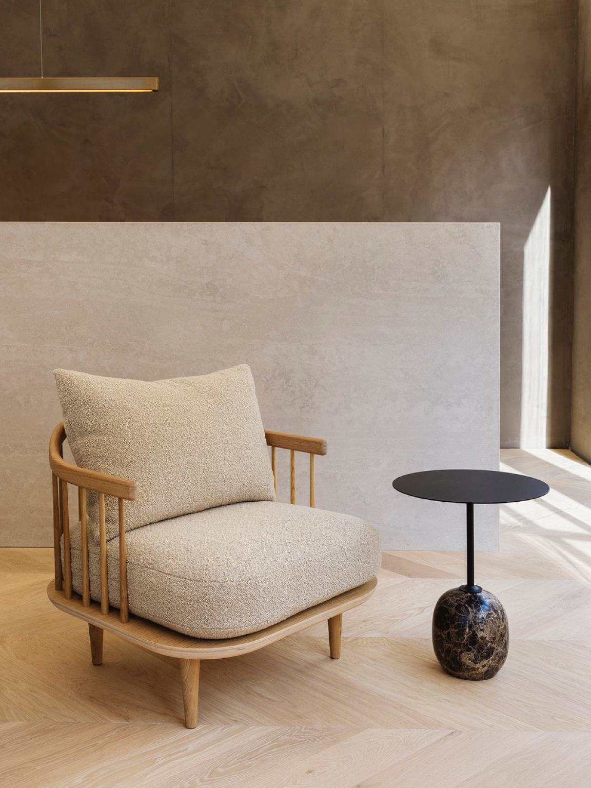 Stylish beige armchair with wooden frame next to a modern black side table, showcasing contemporary interior design trends.