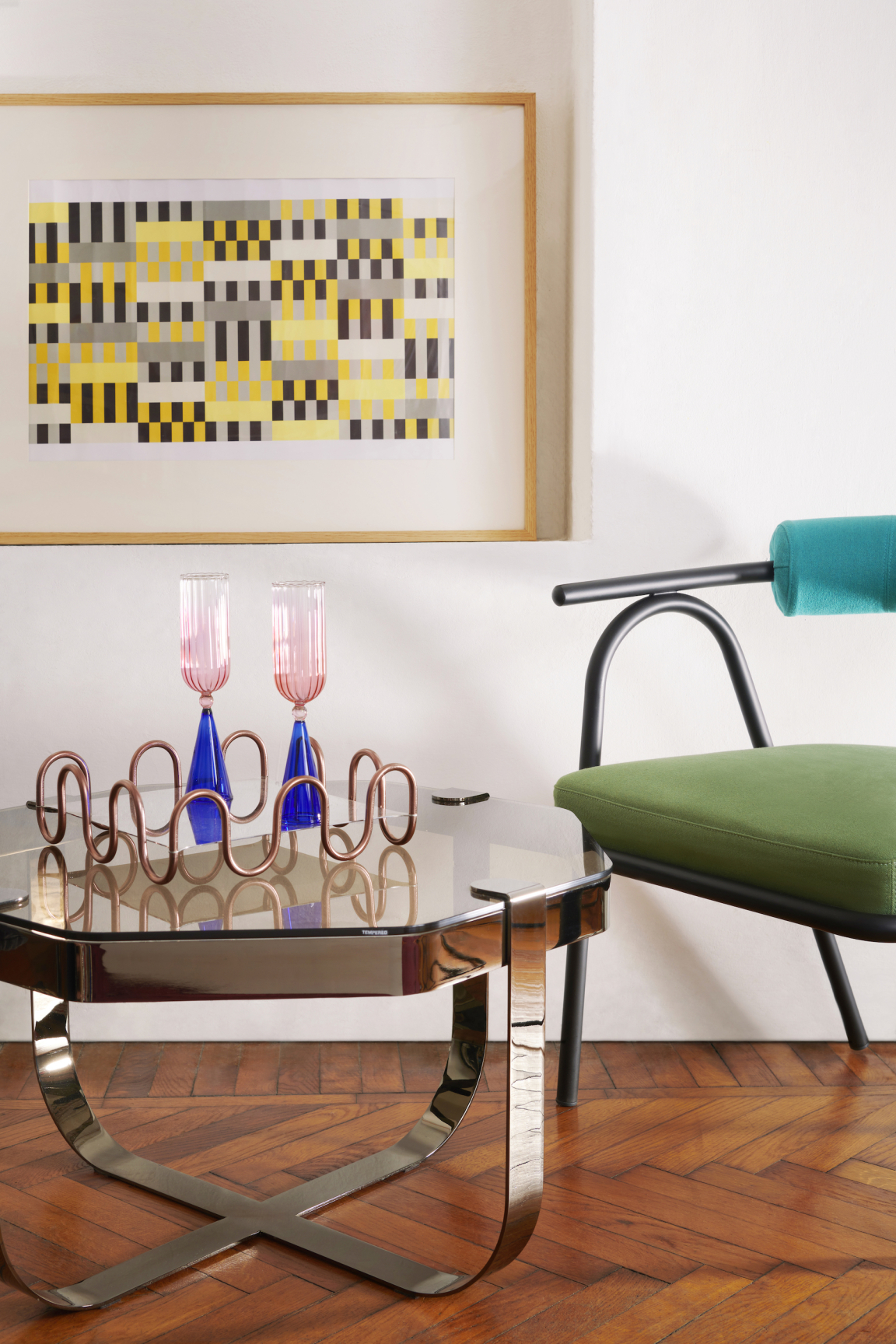 Modern interior featuring a stylish green chair, colorful glassware, and an abstract painting by Serena Confalonieri.